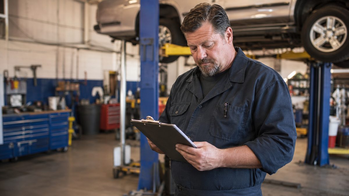 Auto repair shop owner reviewing MCA debt in their garage